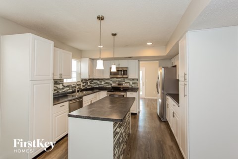 A modern kitchen with white cabinets and a black island.