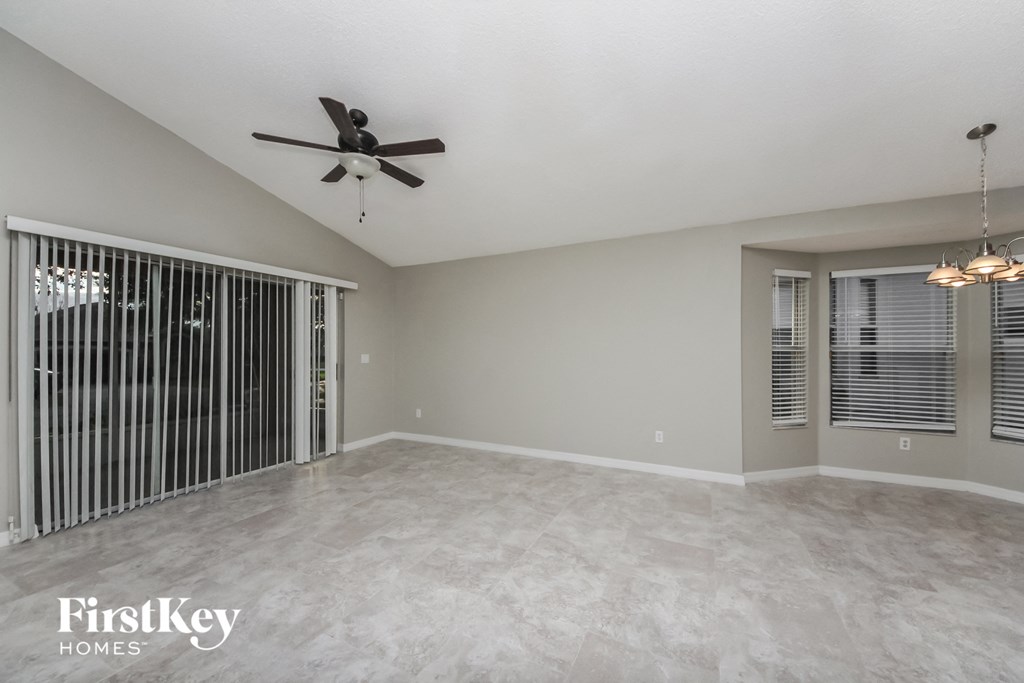 A spacious room with a ceiling fan and a sliding door.