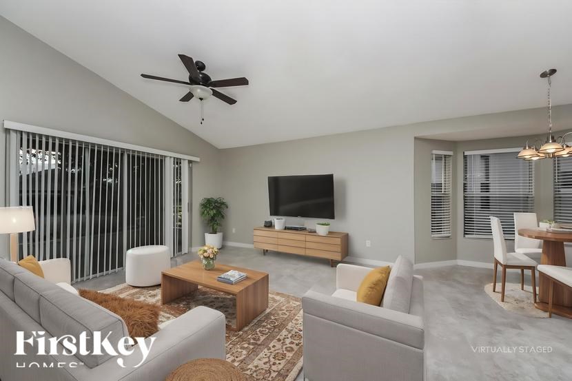 A living room with a grey couch, a coffee table, a television, and a ceiling fan.