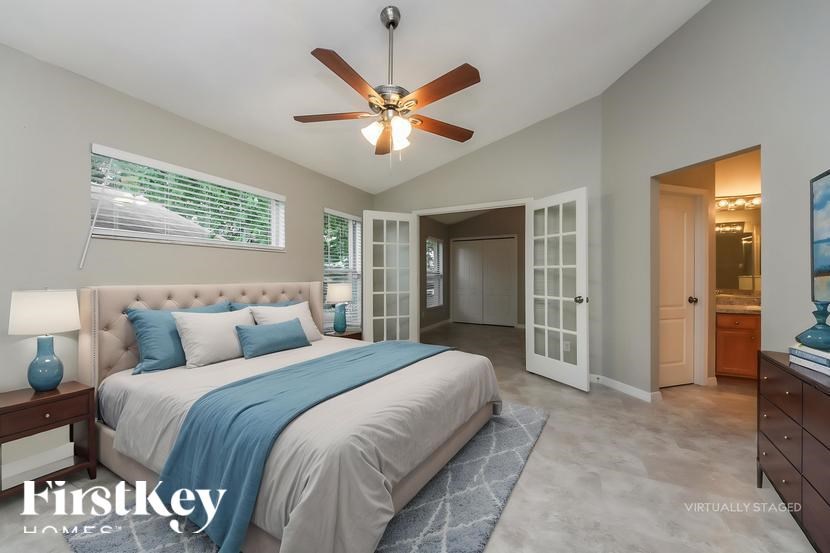 A bedroom with a large bed and a ceiling fan.