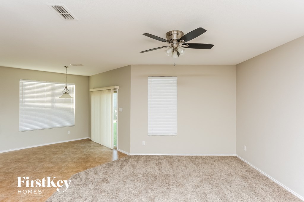 an empty living room with a ceiling fan and a window