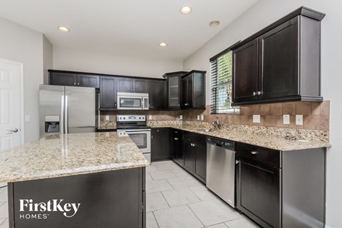 a kitchen with black cabinets and granite counter tops and stainless steel appliances