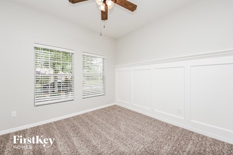a bedroom with white walls and carpet and a ceiling fan