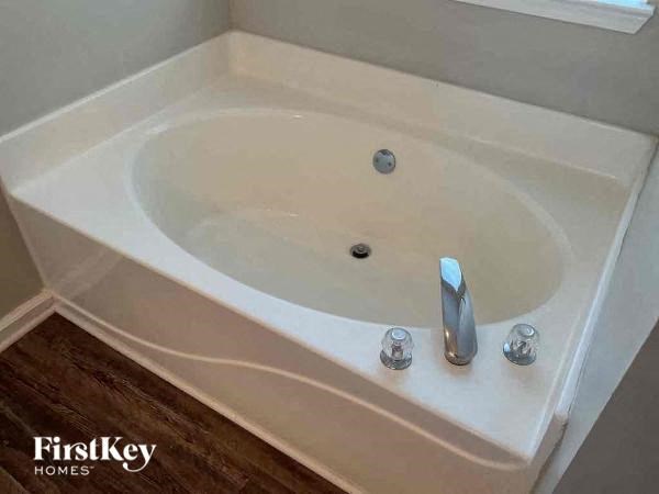 A white bath tub with a silver faucet and two silver handles.