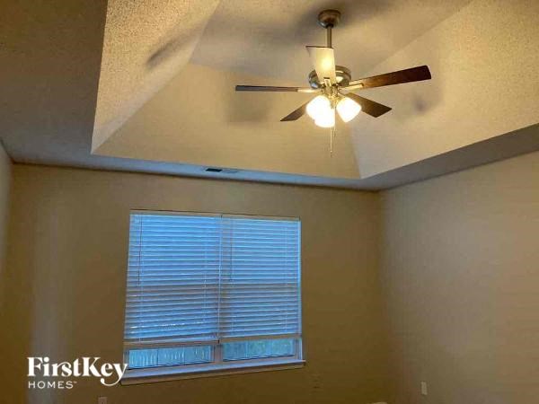 A room with a ceiling fan and a window with blinds.