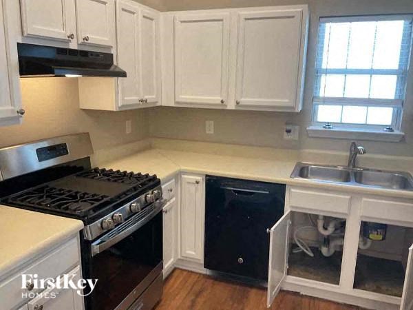 A kitchen with white cabinets and a black stove top oven.