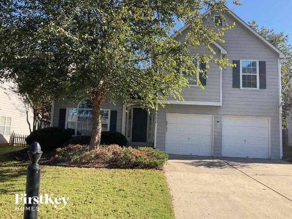 A house with a garage and a tree in front of it.