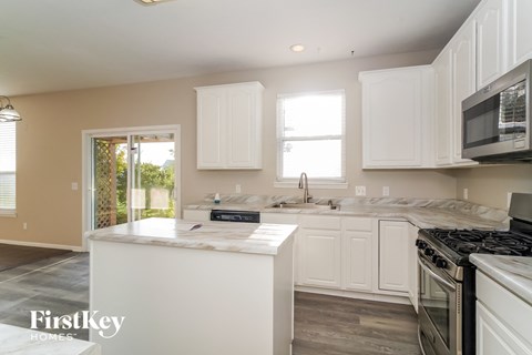 A kitchen with white cabinets and a marble countertop.