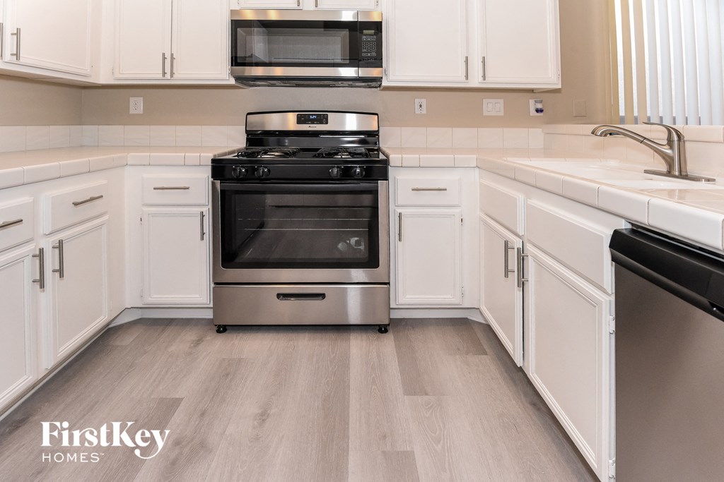 a kitchen with white cabinets and a stove and microwave