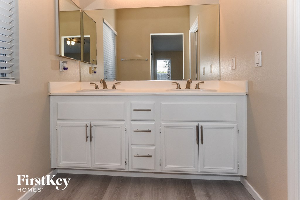 a bathroom with white cabinets and a sink and a mirror