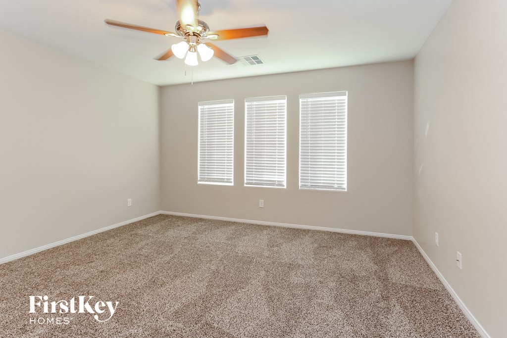 a empty room with a ceiling fan and three windows