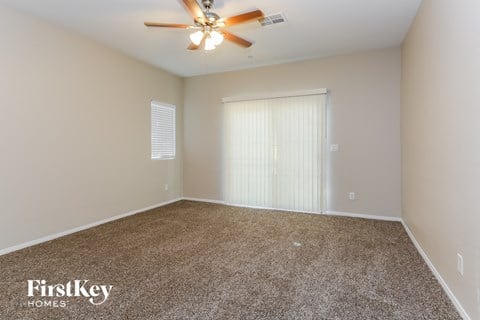 a spacious living room with carpet and a ceiling fan
