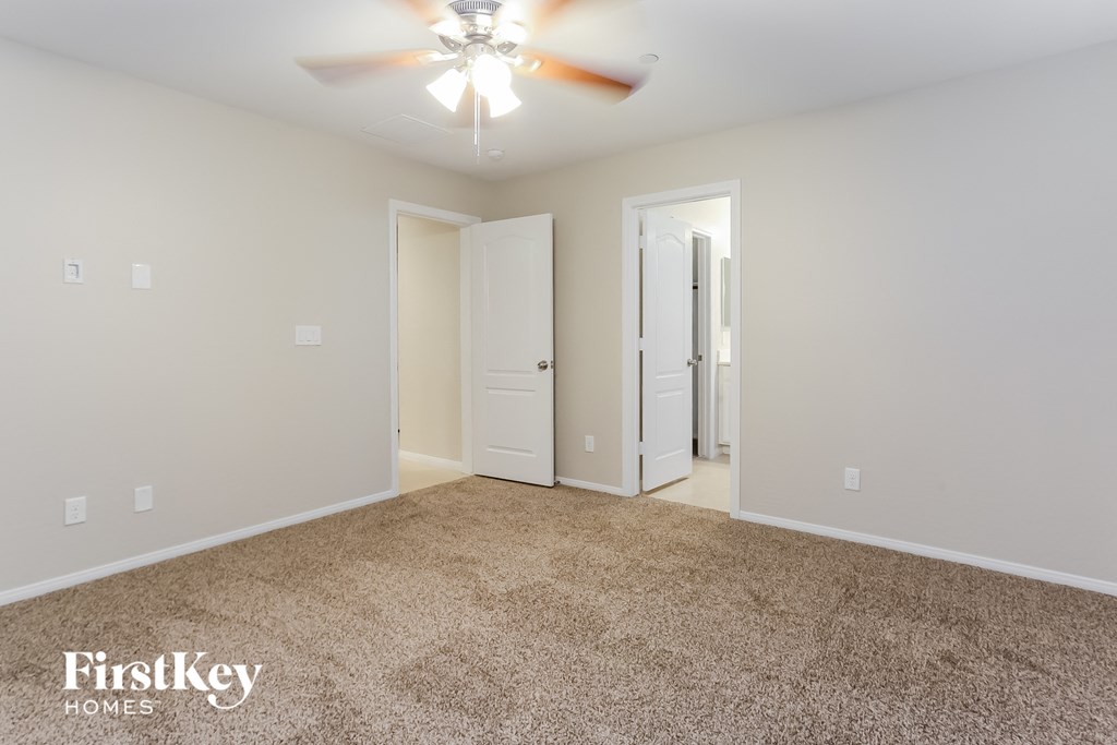 a spacious living room with carpet and a ceiling fan