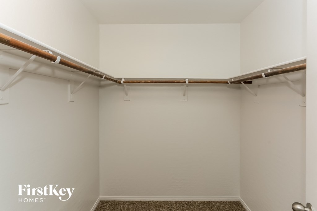 a walk in closet in a white room with pipes on the wall