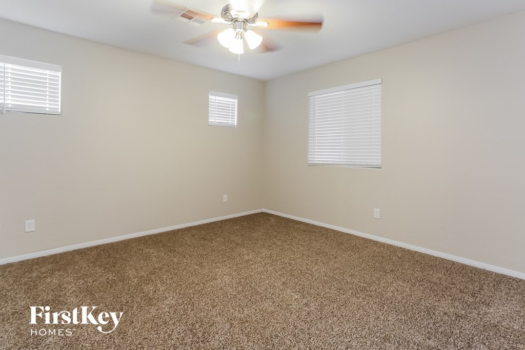 the spacious bedroom with carpeting and a ceiling fan