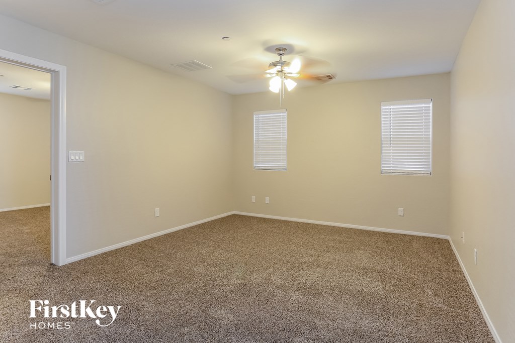 a empty living room with carpet and a ceiling fan