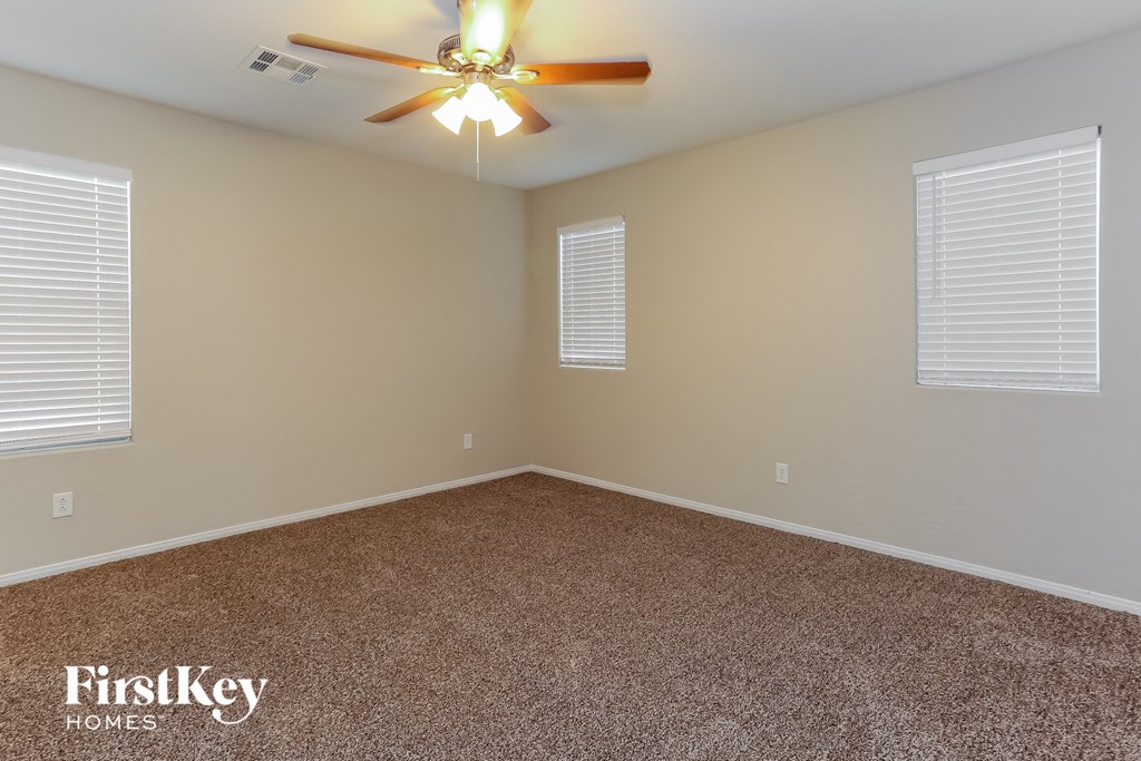 the bonus room has a ceiling fan and two windows