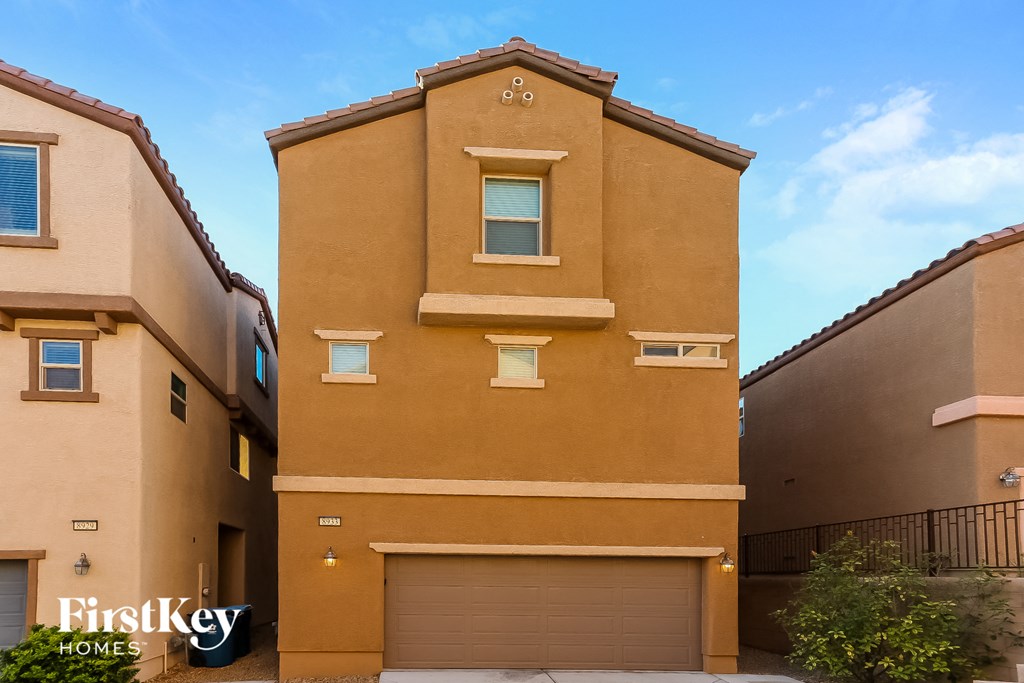 a tan building with two garage doors and a blue sky