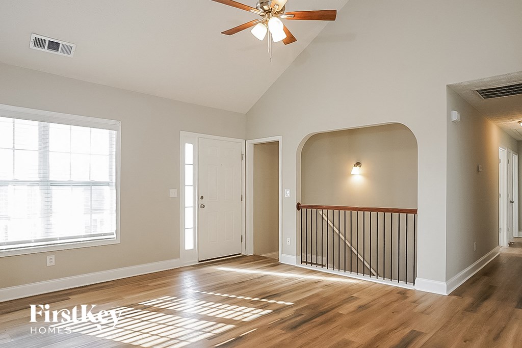 A spacious room with a ceiling fan and wooden flooring.
