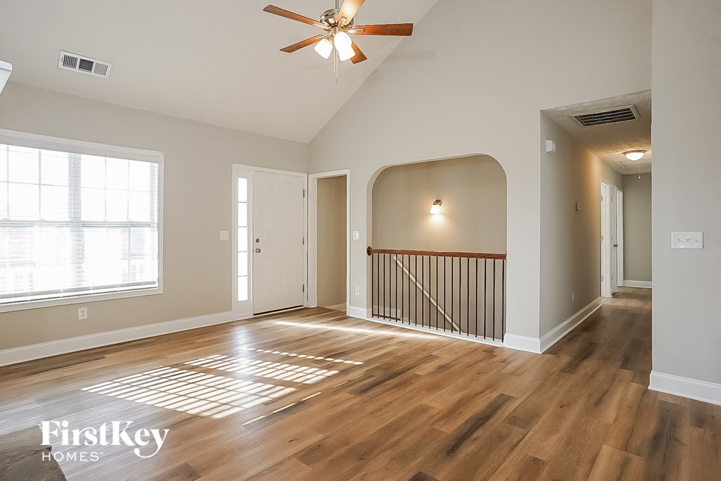 A spacious room with wooden floors and a ceiling fan.