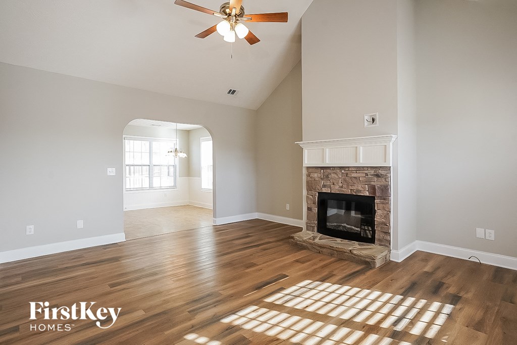 A spacious living room with a fireplace and a ceiling fan.