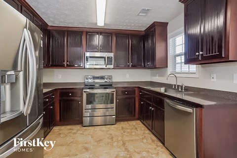 A kitchen with brown cabinets and a stainless steel refrigerator.