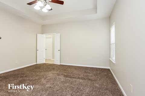 a bedroom with a carpeted floor and a ceiling fan