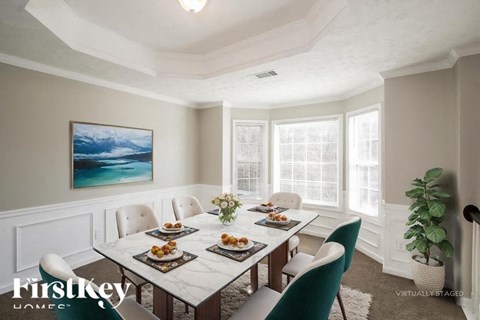 A dining room with a white table and chairs, a painting on the wall, and a plant on the side table.