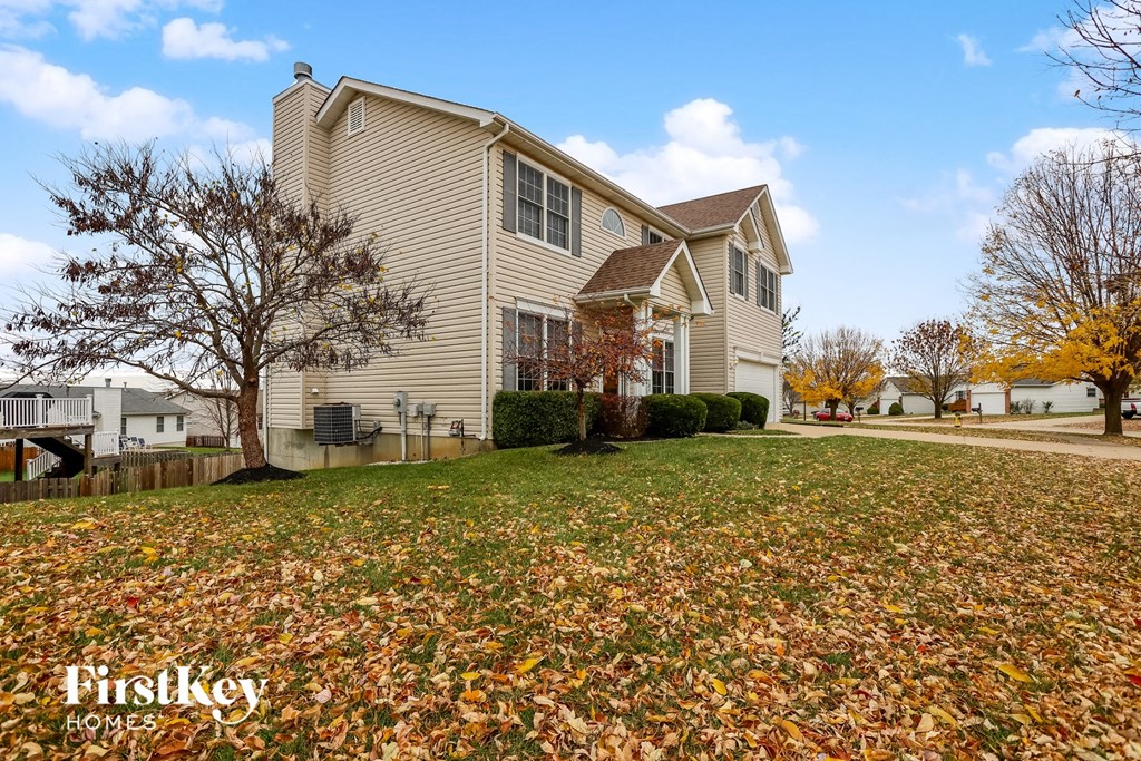 A house with a lawn full of fallen leaves in front of it.