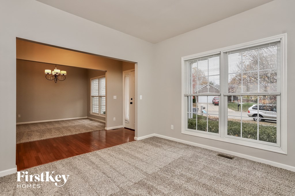 A room with a carpeted floor and a chandelier.