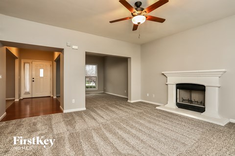 A spacious living room with a fireplace and a ceiling fan.
