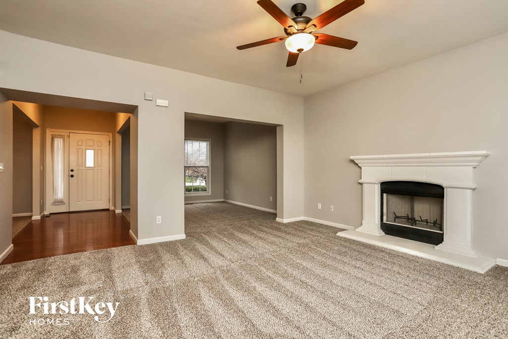 A spacious living room with a fireplace and a ceiling fan.