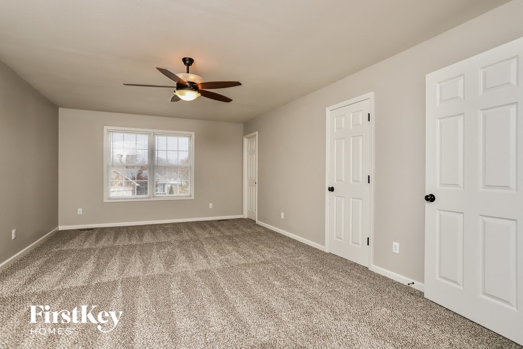 A spacious room with a ceiling fan and two doors.
