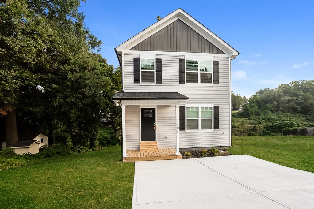 a small white house with a sidewalk in front of it
