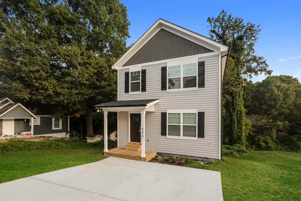 a small gray house with a porch and a driveway