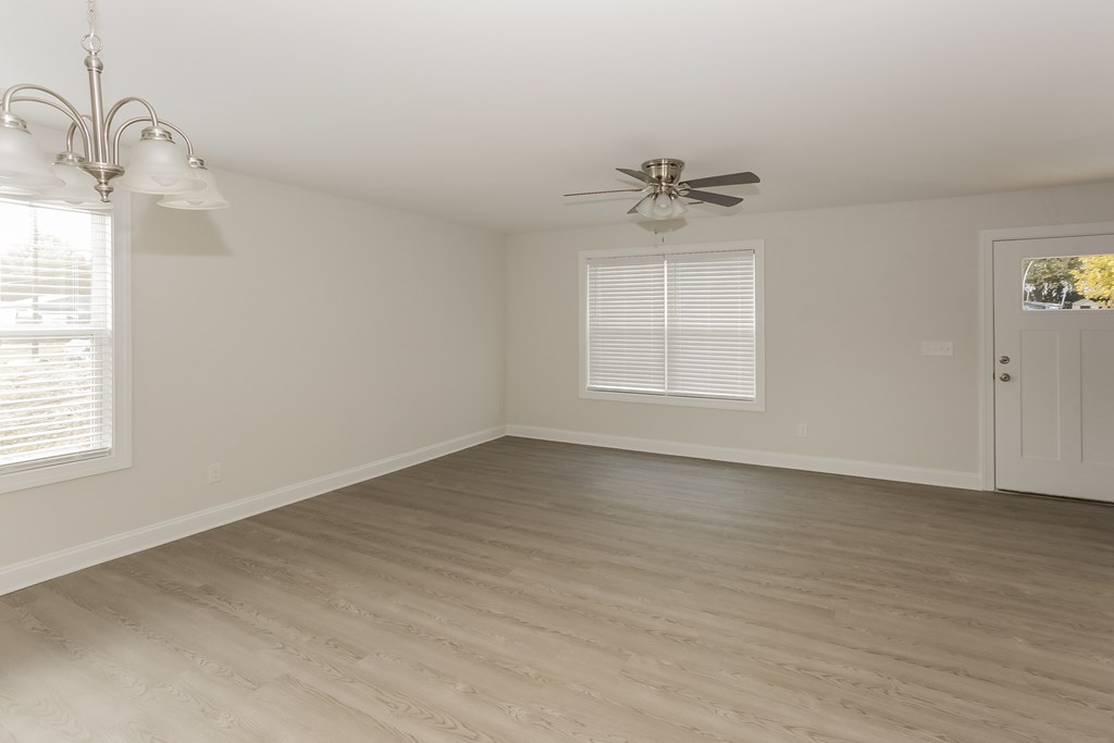 an empty living room with wood floors and a ceiling fan