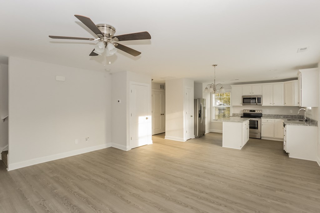 a renovated living room and kitchen with a ceiling fan