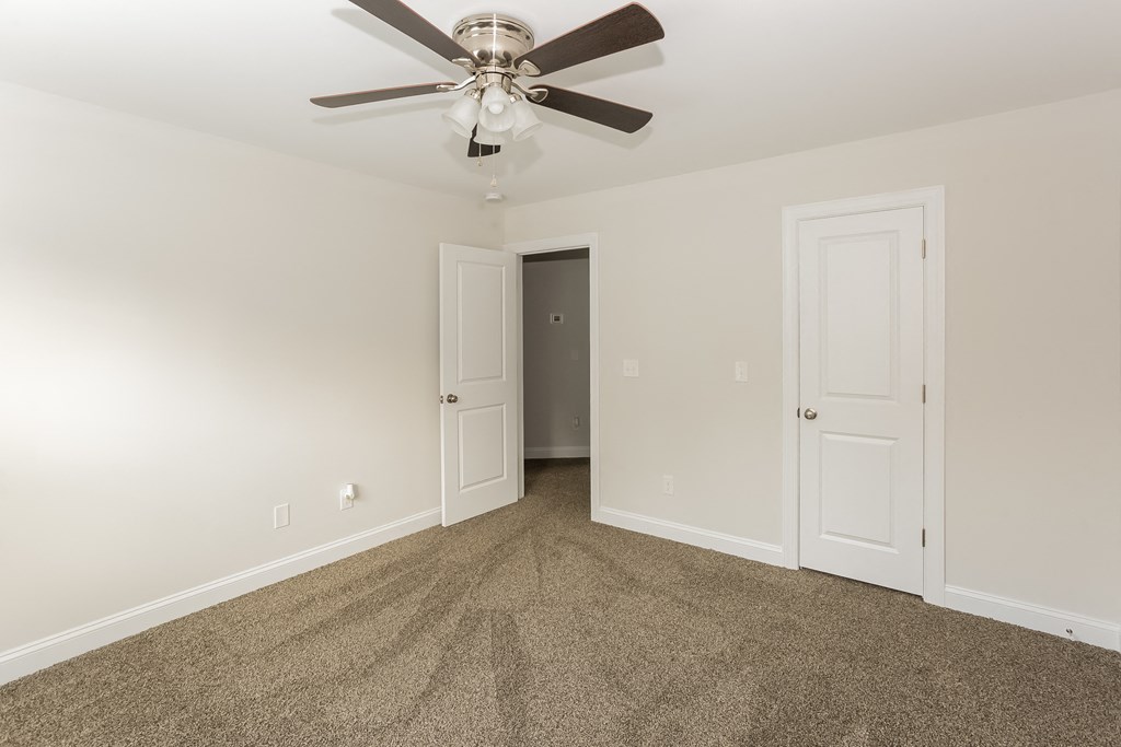 an empty living room with carpet and a ceiling fan