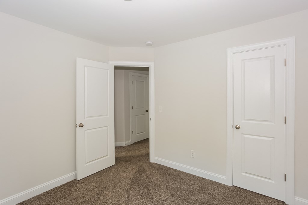 a bedroom with white walls and two doors and a closet
