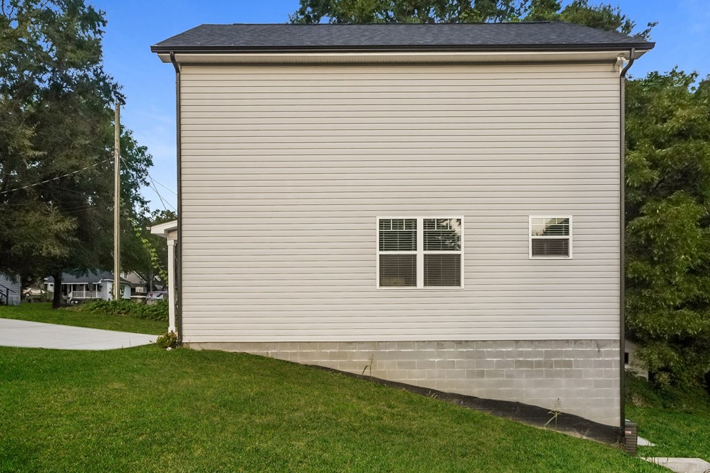 the side of a building with a sidewalk and grass