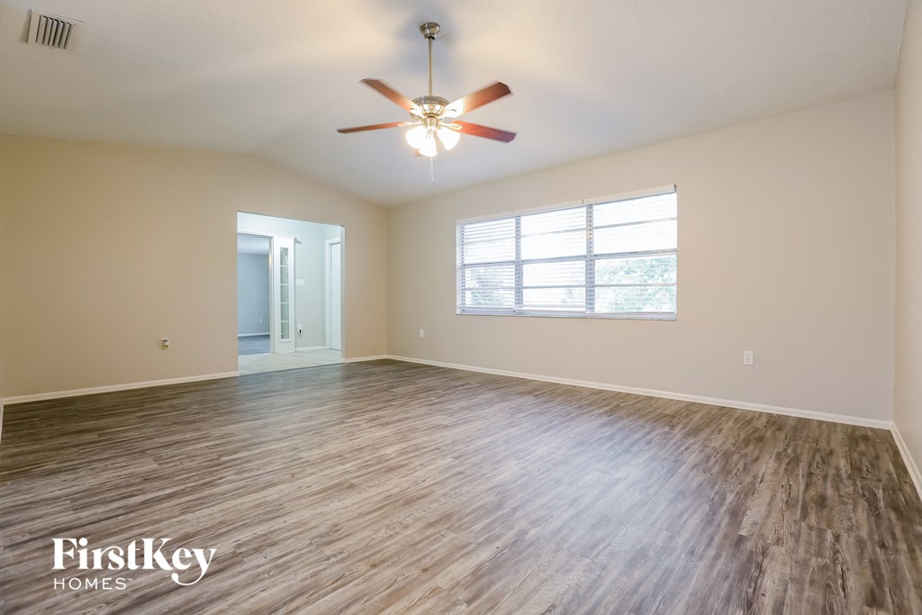 A spacious room with a ceiling fan and wooden flooring.