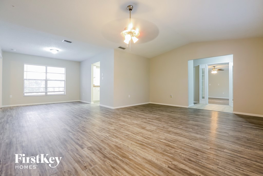 A spacious room with wooden flooring and a ceiling light fixture.