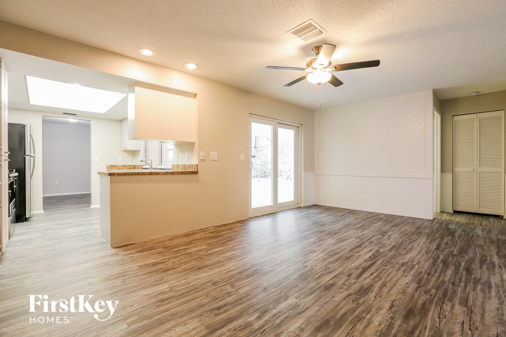 A spacious room with wooden flooring and a ceiling fan.