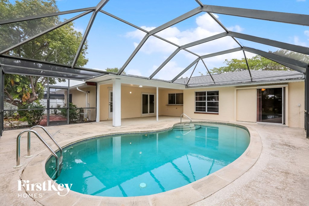 A swimming pool is surrounded by a concrete floor and a glass ceiling.