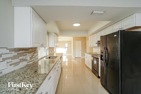A kitchen with a black refrigerator and white cabinets.