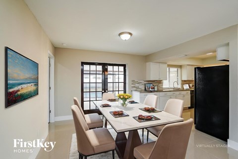 A dining room with a table set for six and a painting on the wall.
