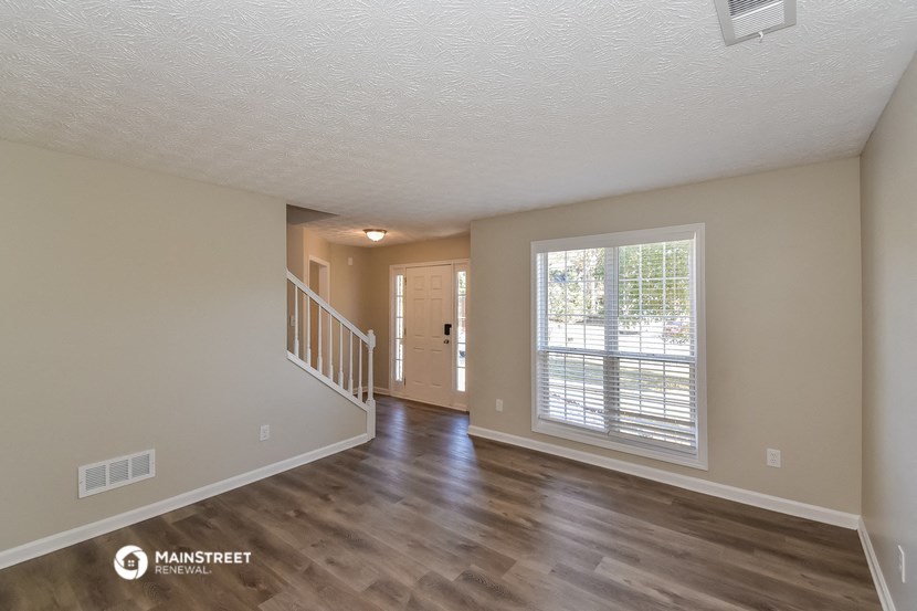 the spacious living room with a large window and wood flooring