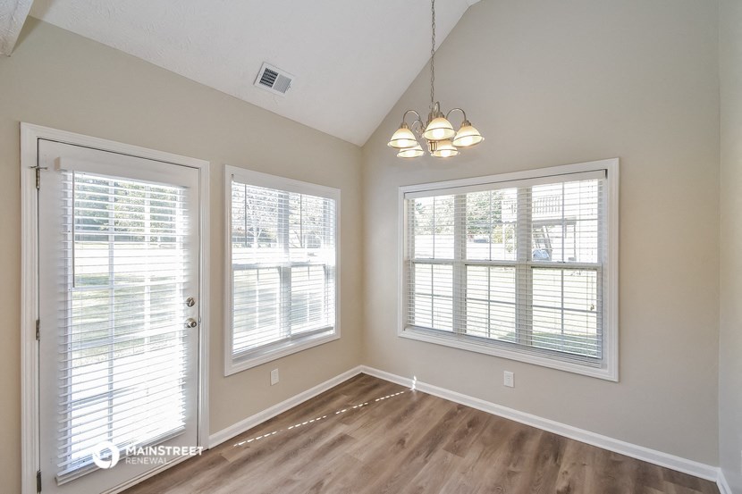 an empty living room with three windows and a door