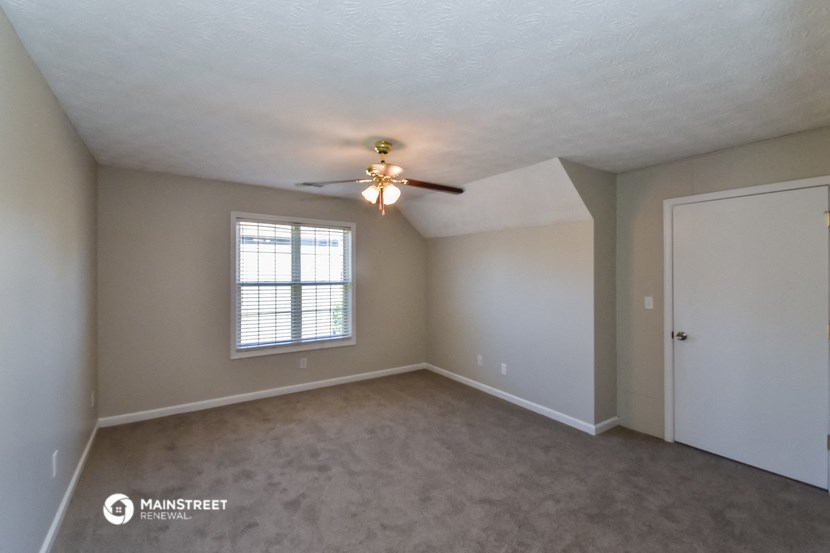 an empty living room with a ceiling fan and a window