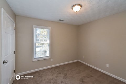 the spacious bedroom with carpet and a window